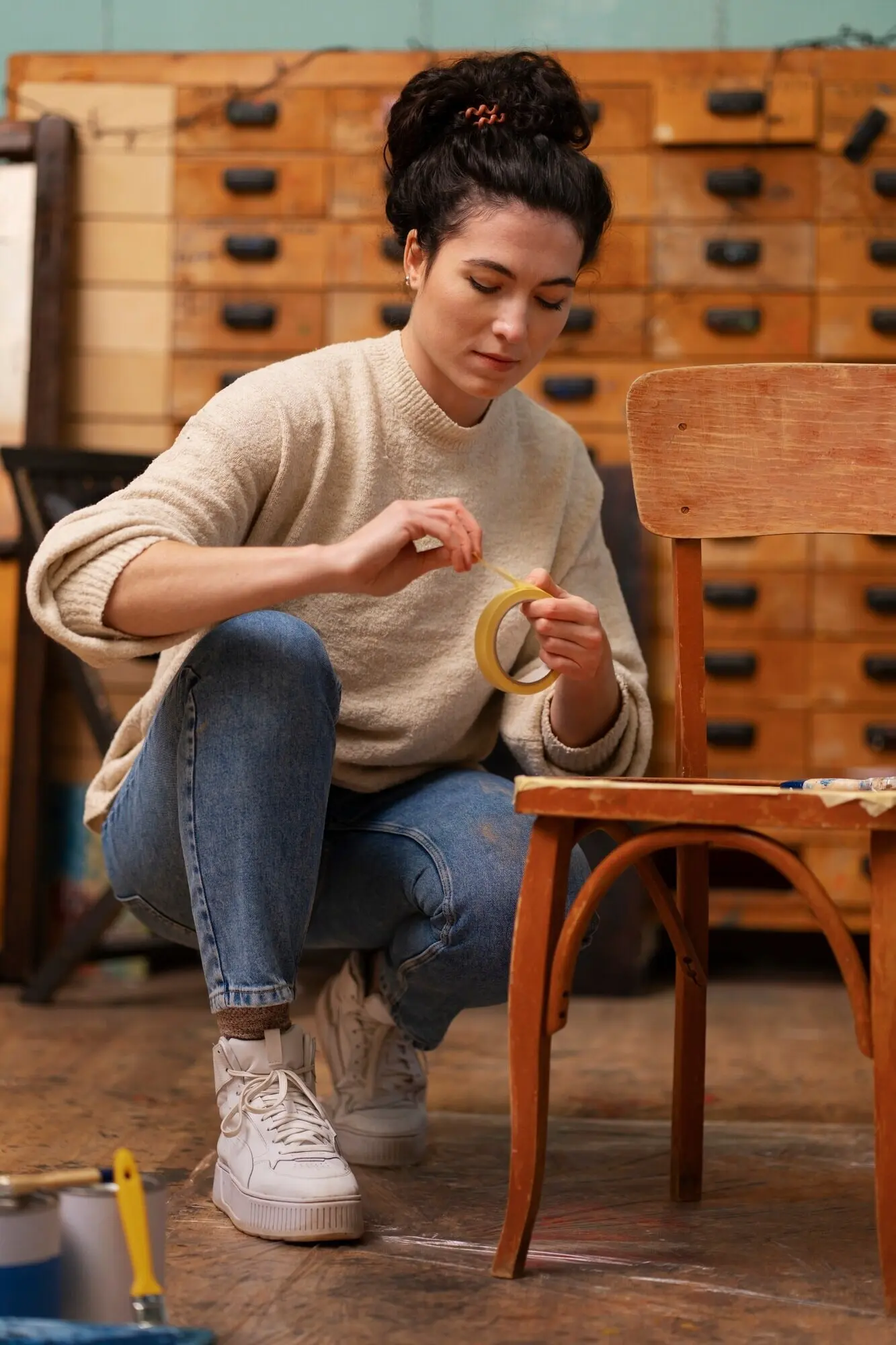 Frau restauriert einen Holzstuhl, Ganzkörperaufnahme